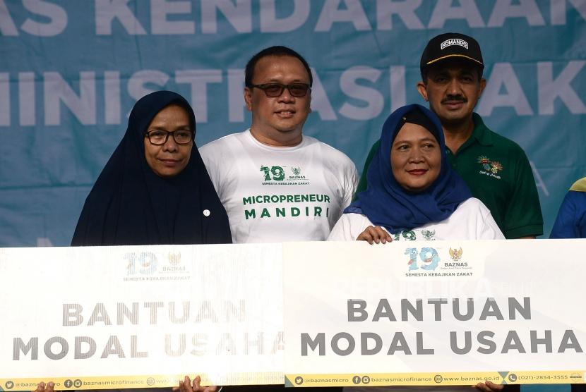 Direktur Pendistribusian dan Pendayagunaan BAZNAS Irfan Syauqi Beik bersama Walikota Jakarta Timur M Anwar berfoto usai menyerahakan modal usaha saat berlangsungnya pasar rakyat Baznas pada ajang Hari Bebas Kendaraan Bermotor (HBKB) di Jalan Pemuda, Rawamangun, Jakarta, Ahad (26/1).