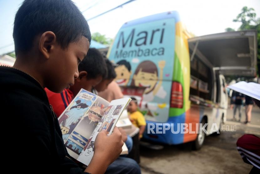 Anak-anak membaca buku di perpustakaan keliling saat berlangsungnya Hari Bebas Kendaraan Bermotor di Kawasan Rawamangun, Jakarta, Ahad (26/1).