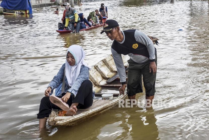 Sejumlah warga menggunakan perahu melintasi genangan banjir di ruas Jalan Anggadireja, Kecamatan Baleendah, Kabupaten Bandung, Ahad (26/11).