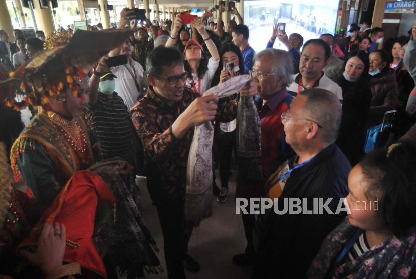 Gubernur Sumatera Barat Irwan Prayitno (kedua kiri) mengalungkan kain kepada salah satu wisatawan asal China saat penyambutan di Bandara Internasional Minangkabau (BIM), Padangpariaman, Sumatra Barat, Ahad (26/1/2020).