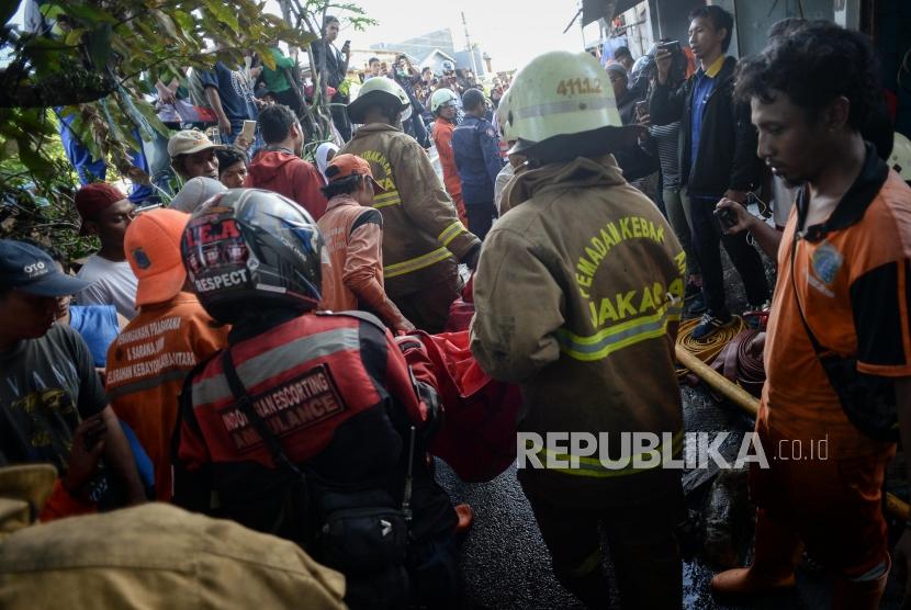Petugas Pemadam Kebakaran membawa kantong jenazah saat evakuasi korban kebakaran di pemukiman padat penduduk kawasan Peninggaran Timur, Kebayoran Lama, Jakarta, Senin (27/1).