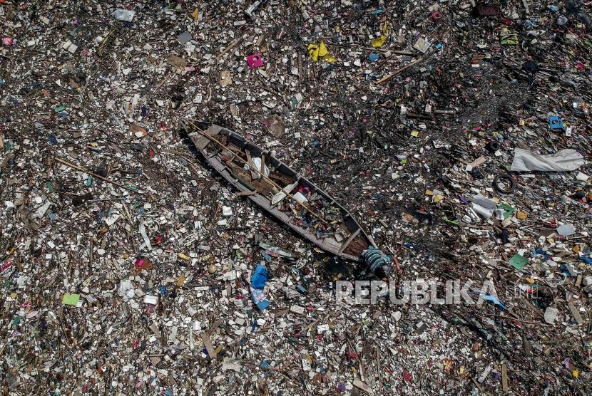 Seorang warga menggunakan perahu untuk memilah sampah plastik di tumpukan sampah (ilustrasi)