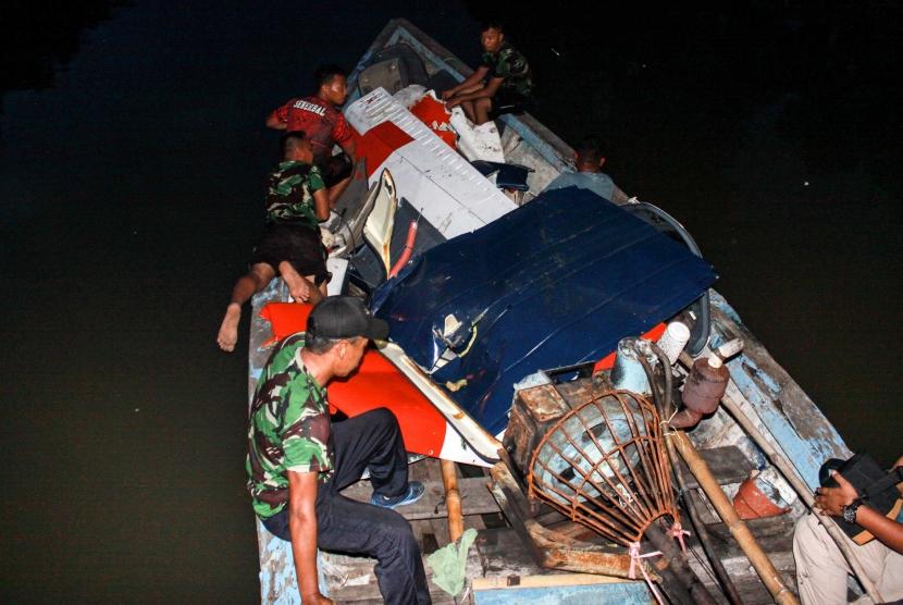 Sejumlah prajurit membawa bagian pesawat latih yang mendarat darurat menggunakan perahu di kawasan Kedungpeluk, Candi, Sidoarjo, Jawa Timur, Selasa (4/2/2020).