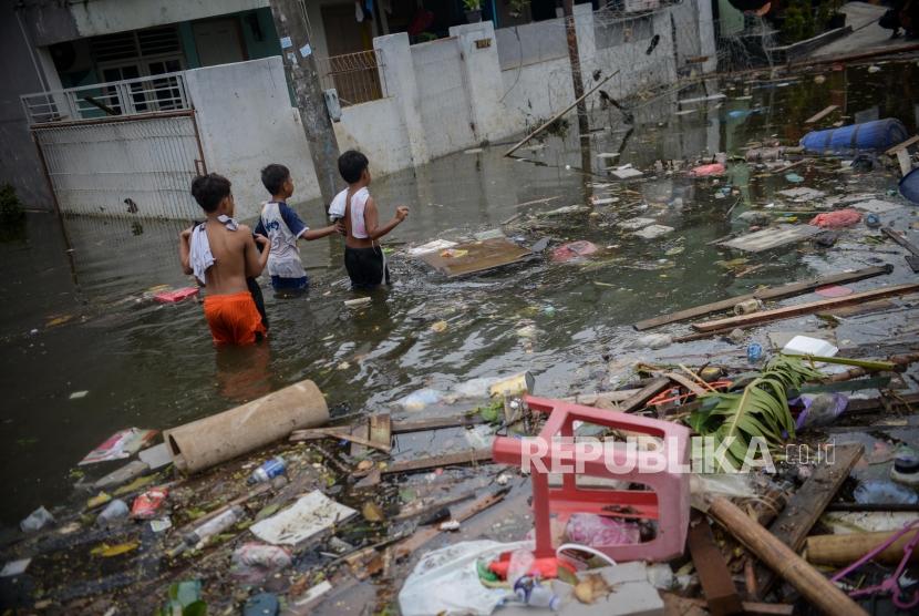 Sejumlah anak berjalan melewati genangan air saat banjir di kawasan Perumahan Periuk Damai, Kota Tangerang. Ratusan petugas kebersihan dari Dinas Lingkungan Hidup membantu bersihkan sisa banjir. Ilustrasi.