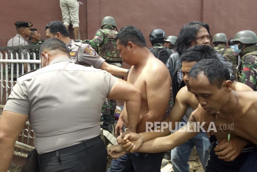Petugas gabungan menggiring narapidana pascakerusuhan di Rumah Tahanan Negara (Rutan) Kelas II B Kabanjahe, Kabupaten Karo, Sumatera Utara, Rabu (12/2/2020).