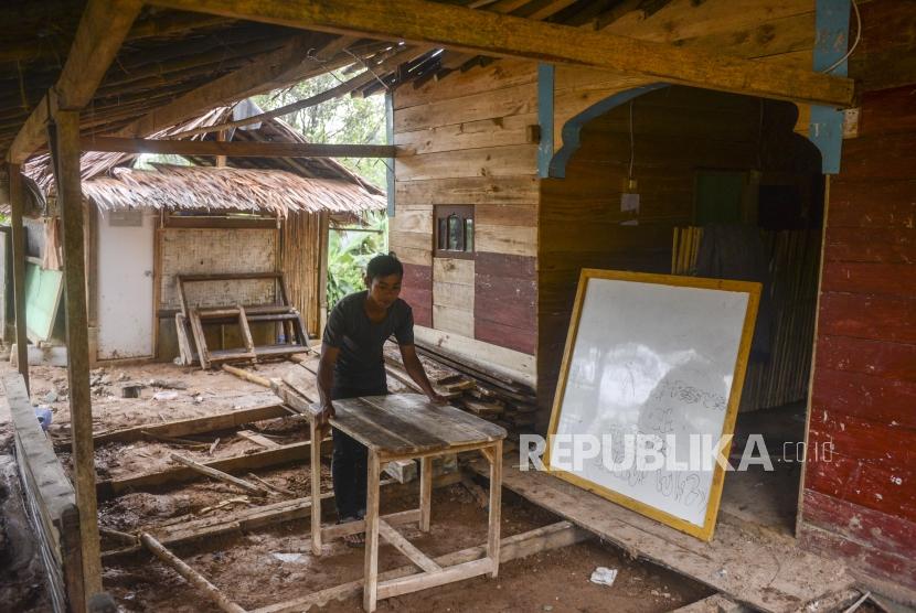 Seorang warga mengangkut meja di pondok pesantren yang hancur akibat bencana alam di Kampung Ciparempeng, Desa Cileuksa, Sukajaya, Kabupaten Bogor, Jawa Barat, Kamis (13/2).