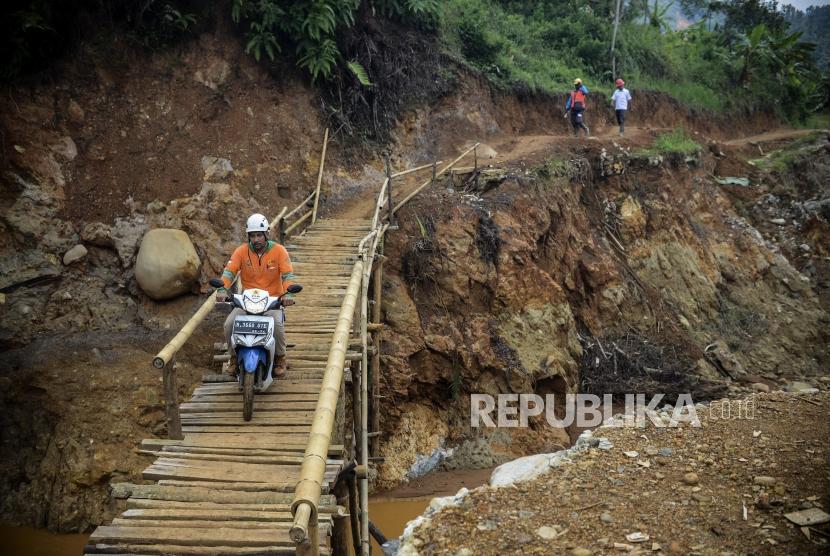 Pengendara motor melintasi jembatan darurat di Desa Cileuksa, Kecamatan Sukajaya, Kabupaten Bogor, Jawa Barat, Kamis (13/2).