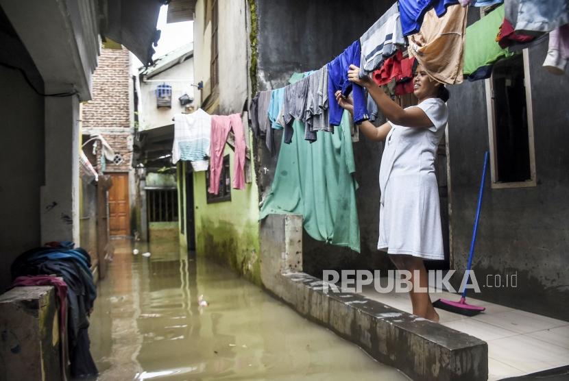 Seorang warga menjemur pakaian di halaman rumahnya yang terendam banjir di Kampung Bojong Asih, Kecamatan Dayeuhkolot, Kabupaten Bandung.