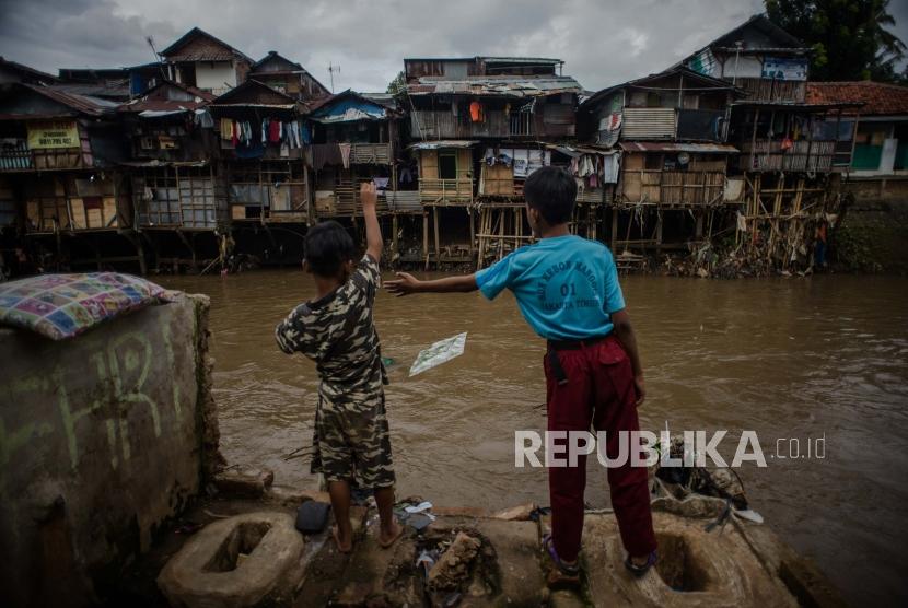 Warga beraktifitas di halaman rumahnya di kawasan aliran Kali Ciliwung, Manggarai, Jakarta, Selasa (18/2).