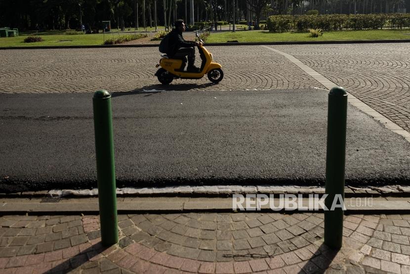 Sejumlah pengendara motor listrik melintas di area percobaan pengaspalan lintasan Formula E non permanen di kawasan Monumen Nasional, Jakarta, Ahad (23/2).