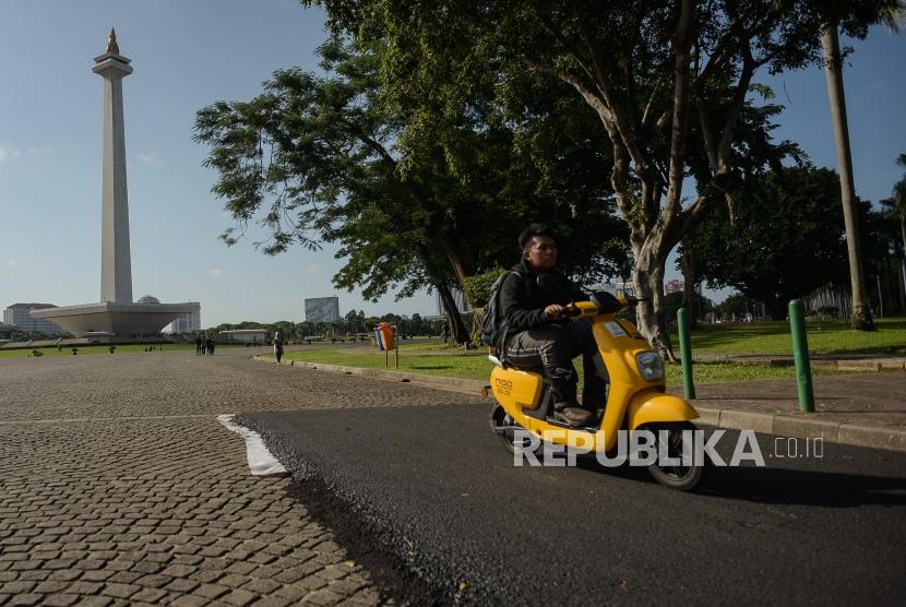 Sejumlah pengendara motor listrik melintas di area percobaan pengasopalan lintasan Formula E non permanen di kawasan Monumen Nasional, Jakarta, Ahad (23/2).