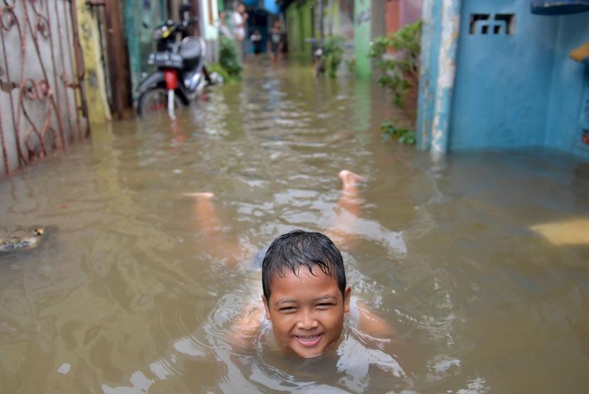 Seorang bocah bermain air banjir yang merendam Jalan Anyer di Menteng, Jakarta, Minggu (23/2/2020).