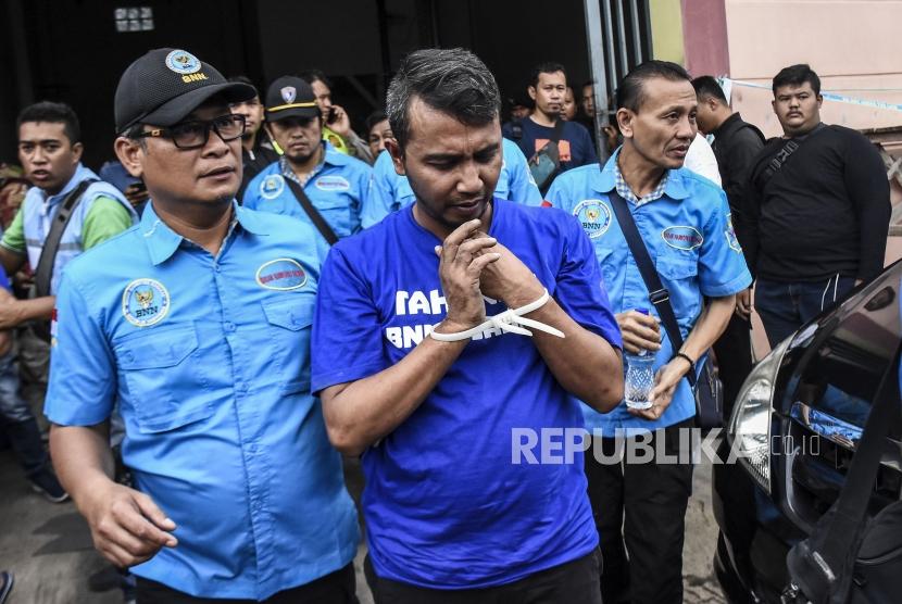 Petugas Badan Narkotika Nasional menggiring tersangka saat penggeledahan rumah produksi narkoba di Jalan Cingised, Kelurahan Cisaranten Endah, Kecamatan Arcamanik, Kota Bandung, Senin (24/2).