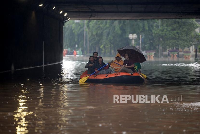 Warga melintasi banjir dengan menggunakan perahu karet dikawasan terowongan Jalan DI Panjaitan, Cawang, Jakarta.