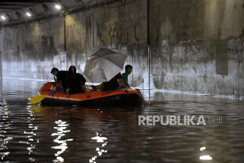 Warga melintasi banjir dengan menggunakan perahu karet dikawasan terowongan Jalan DI Panjaitan, Cawang, Jakarta, Selasa (25/2).