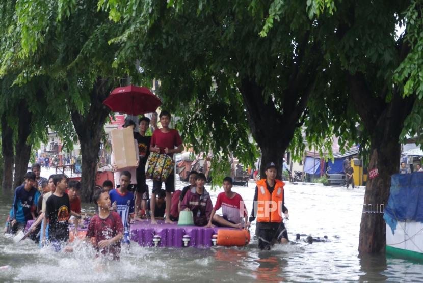 Warga bersama-sama mendorong pelampung rakitan untuk mengangkut motor dan masyarakat agar terhindar dari banjir di jalan Sunter Kemayoran Jakarta, Selasa (25/2).