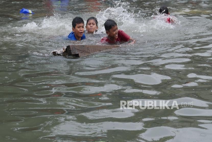 Sejumlah anak bermain dengan melompat untuk berenang ke dalam kali Item di Jalan Sunter Kemayoran, Jakarta, Selasa (25/2). Pascabanjir sejumlah penyakit mengintai tubuh.