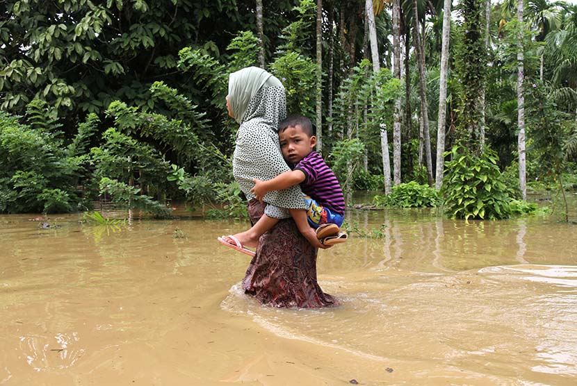  Seorang warga mengendong anaknya untuk melintasi banjir di Desa Buket Liteung, Kecamatan Langkahan, Aceh Utara, Aceh, Senin (8/2).  (Antara/Syifa Yulinnas)