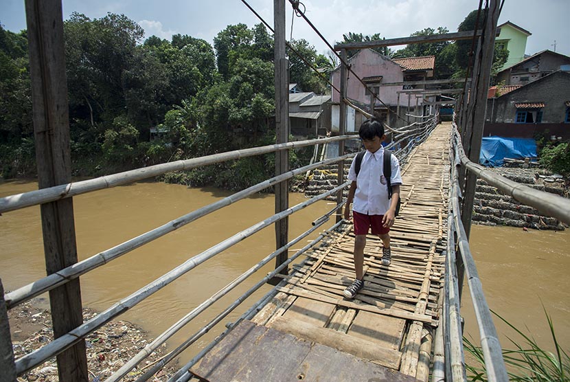Seorang pelajar menyeberang melalui jembatan gantung di atas Sungai Ciliwung menuju kawasan Kampung Poncol di Jakarta, Senin (4/4). (Antara/Widodo S. Jusuf)