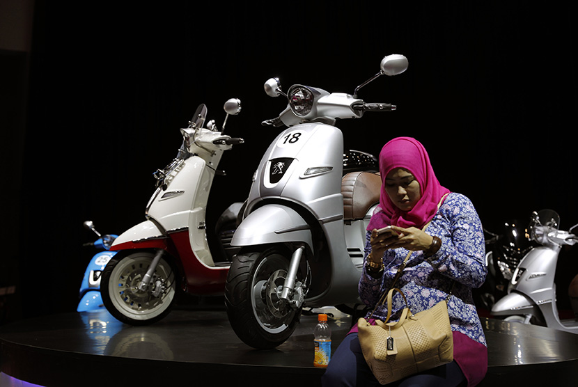 Seorang pengunjung duduk disamping motor skutik Peogeot dalam ajang Indonesian International Motor Show (IIMS) 2016, Jakarta.