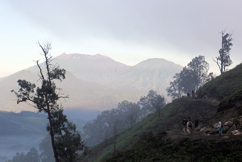 Sejumlah wisatawan mendaki gunung Ijen dengan latar belakang gunung Raung di Paltuding, Banyuwangi, Jawa Timur. (Antara/Budi Candra Setya)
