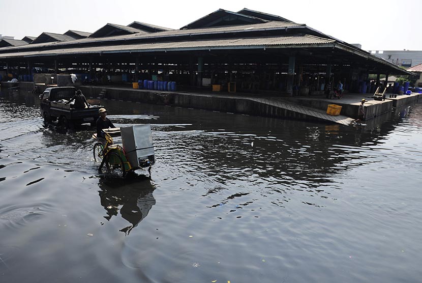 Pengendara becak melintasi banjir rob di Kawasan Pasar Ikan Muara Baru, Jakarta, Selasa (7/6). (Antara/Wahyu Putro A)