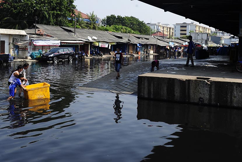 Pekerja membawa kotak berisi ikan laut ketika melintasi banjir rob di Kawasan Pasar Ikan Muara Baru, Jakarta, Selasa (7/6). (Antara/Wahyu Putro A) 