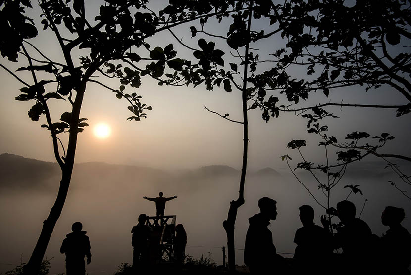 Wisatawan menikmati suasana matahari terbit di Bukit Panguk, Kediwung, Mangunan, Yogyakarta, Senin (11/7). (Antara/Sigid Kurniawan)