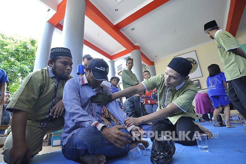 Petugas menetralisir peserta kesarukan saat 'Belajar Ruqyah' di Dojo Konporyo 67 Academy, Jl Leuwi Anyar Raya, Kota Bandung, Ahad (24/7).(foto : Mahmud Muhyidin)