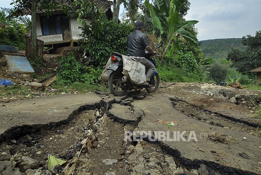 Pengendara motor melintas di bangunan yang roboh akibat pergerakan tanah di Kampung Cikatomas, Sasak Gantung, Desa Citatah, Kecamatan Cipatat, Kabupaten Bandung Barat, Rabu (23/11).
