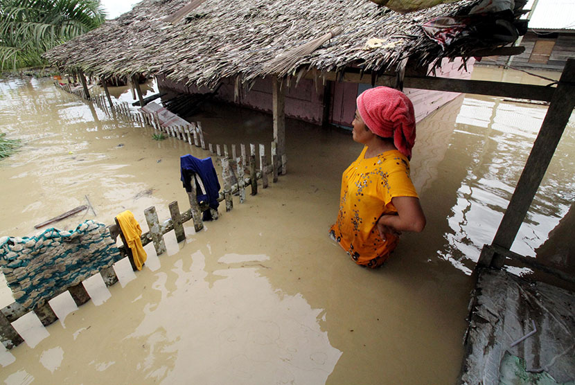 Warga berdiri di teras rumahnya yang terendam banjir di Desa Nga, Lhoksukon, Aceh Utara, Aceh, Rabu (4/1). 