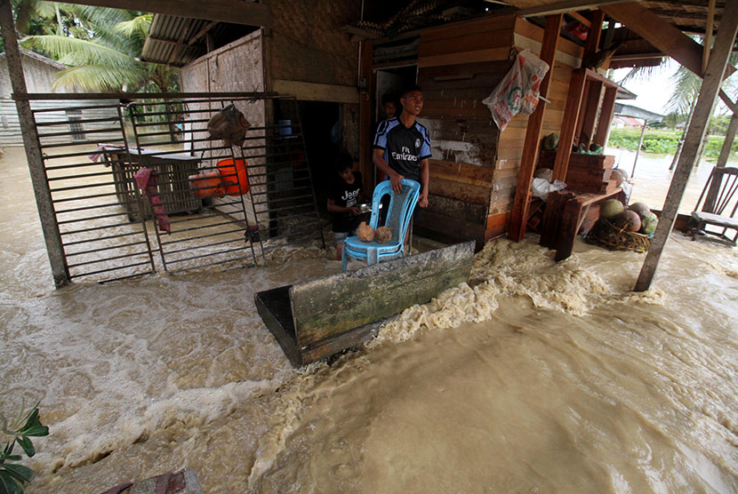 Warga berdiri di teras rumahnya yang terendam banjir di Desa Nga, Lhoksukon, Aceh Utara, Aceh, Rabu (4/1). 