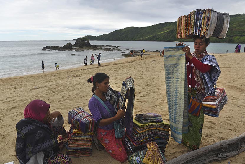 Para pedagang souvenir menjajakan dagangannya berupa kain khas Suku Sasak kepada wisatawan di pantai Kuta, Lombok, Nusa Tenggara Barat, Jumat (20/1).
