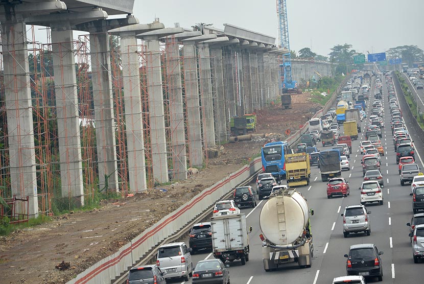 Kendaraan melintas di samping pembangunan  proyek Light Rail Transit (LRT) di Cibubur, Jaktim, Selasa (14/2). 