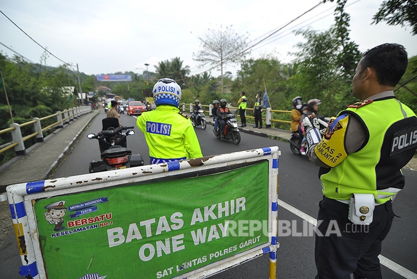   Petugas polisi mengatur lalu lintas arus mudik saat penerapan satu arah di Jalan Sasak Beusi, Kecamatan Limbangan, Kabupaten Garut, Jumat (23/6).