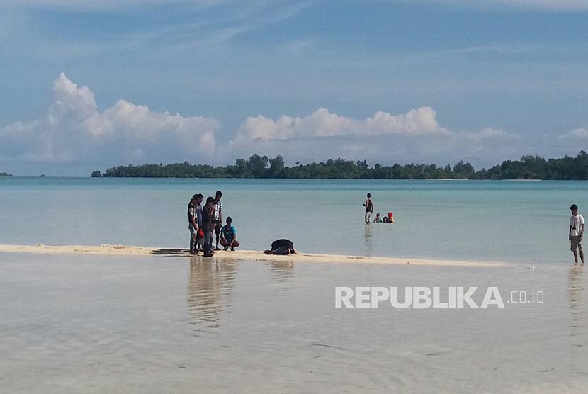 Wisatawan bermain di pasir putih yang menyembul di permukaan dangkal perairan Pulau Daga, Kepulauan Widi, Kabupaten Halmahera Selatan, Provinsi Maluku Utara, Sabtu (28/10).