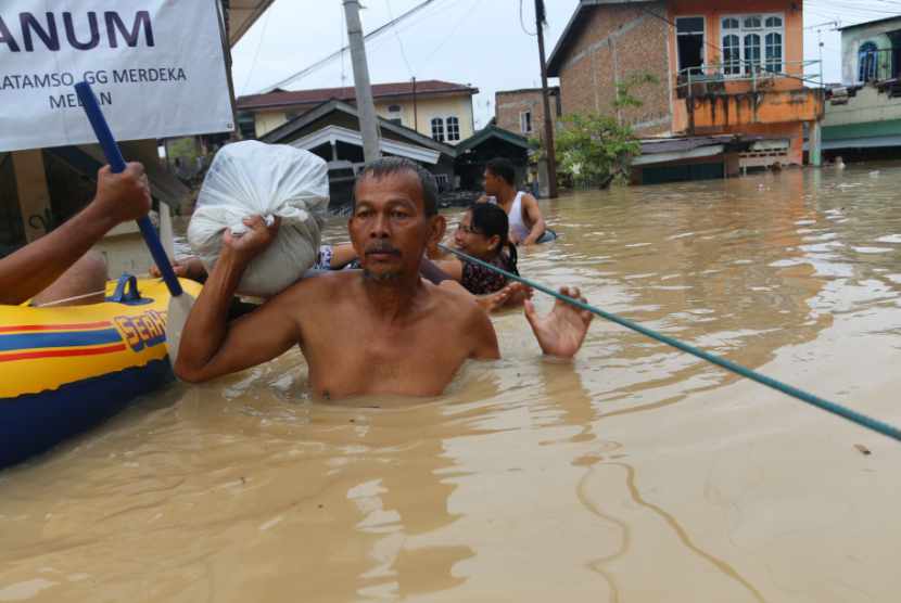 Sejumlah warga melintasi banjir yang merendam pemukiman penduduk di pinggiran Sungai Deli, Kecamatan Medan Maimun, Medan, Sumatera Utara, Selasa (7/11).
