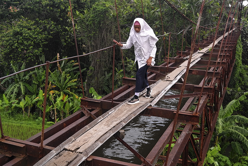 Siswa menyeberangi jembatan gantung yang difungsikan sebagai saluran air, di Ngemplak, Boyolali, Jawa Tengah, Senin (13/11).