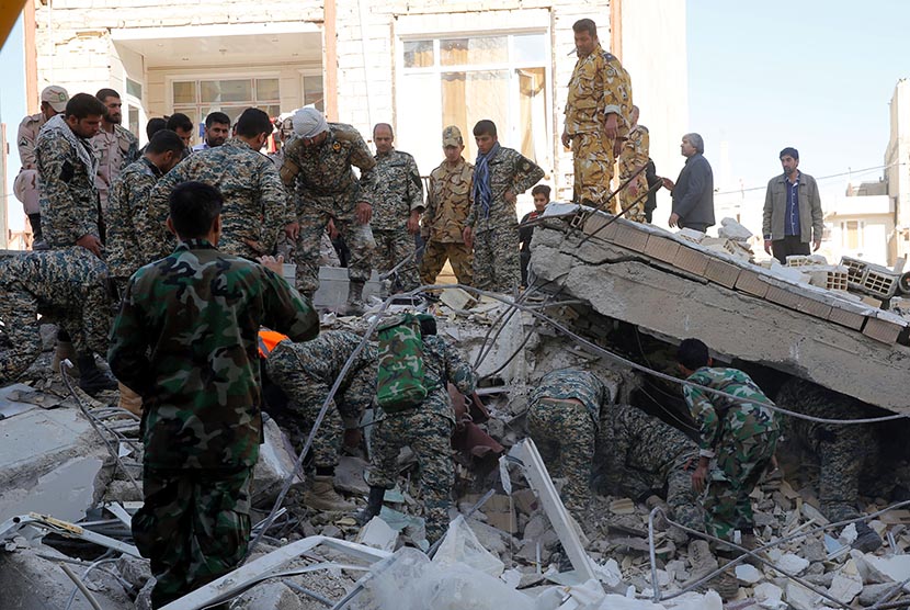  Regu penyelamat mencari korban di bawah reruntuhan sebuah bangunan yang hancur akibat gempa di kota Sarpol-e-Zahab di Provinsi Kermanshah, Iran, Senin (13/11).