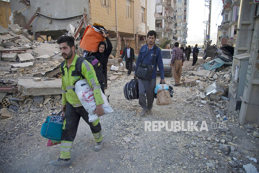  Warga mengevakuasi barang-barang milik mereka dari reruntuhan bangunan yang hancur akibat gempa di kota Sarpol-e-Zahab di Provinsi Kermanshah, Iran, Senin (13/11).
