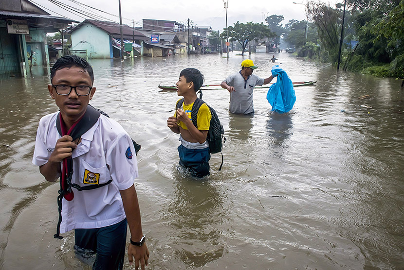 Warga melintasi banjir di kawasan Baleendah, Kabupaten Bandung, Jawa Barat, Senin (13/11). 