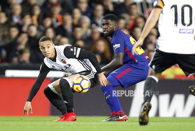  Pemain Barcelona Samuel Umtiti berebut bola dengan pemain Valencia Rodrigo pada laga La Liga Spanyol di stadion Mestalla, Valencia, Senin (27/11) dini hari WIB.