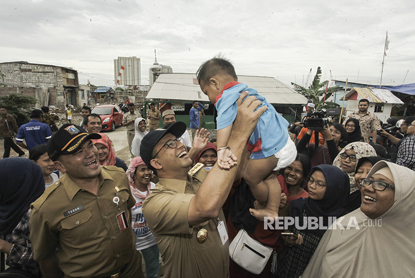 Gubernur DKI Jakarta Anies Baswedan mengangkat seorang anak warga setempat saat meninjau Kampung Akuarium, di Jakarta, Senin (27/11). 