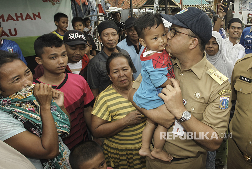 Gubernur DKI Jakarta Anies Baswedan mencium seorang anak warga setempat saat meninjau Kampung Akuarium, di Jakarta, Senin (27/11). 