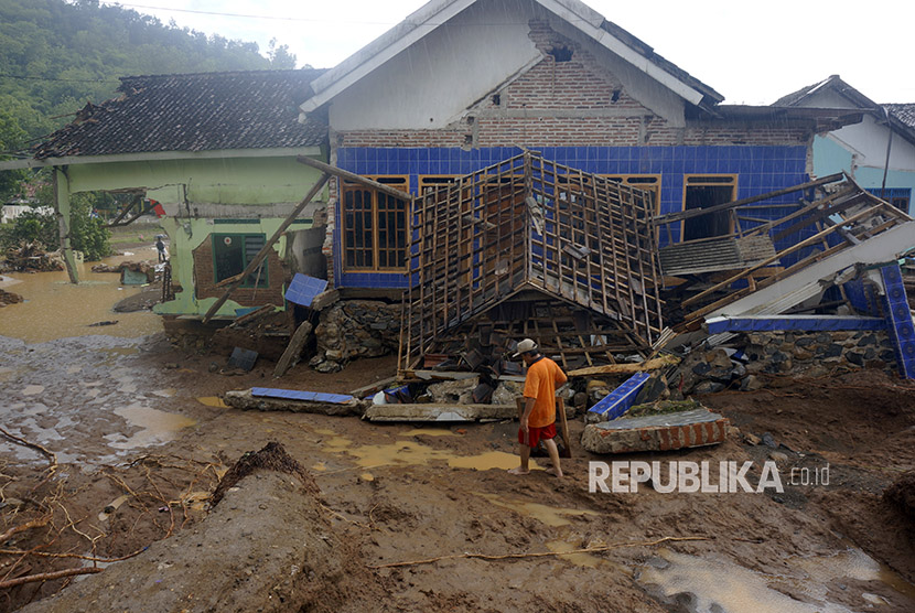 Warga menyeberangi banjir bandang yang memutus jalur lintas selatan Desa Hadiwarno, Pacitan, Jawa Timur, Selasa (28/11). 