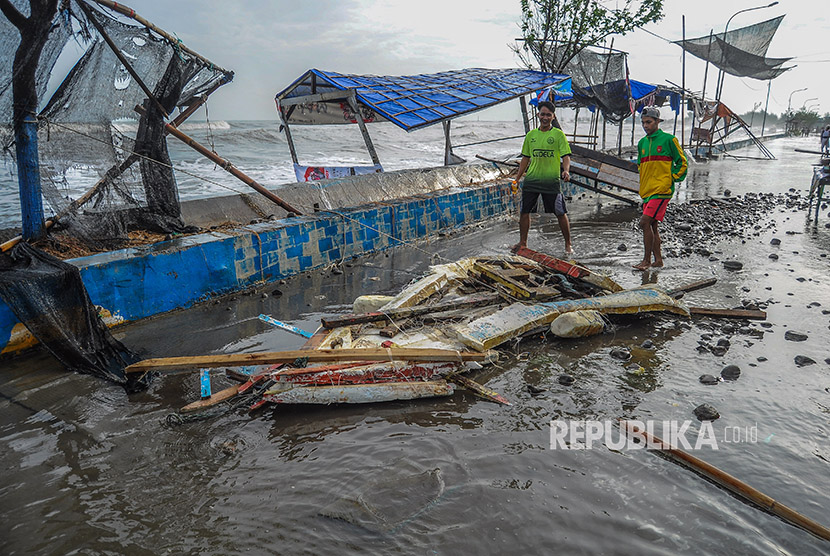 Sejumlah warga melintas di tenda warung yang roboh akibat ombak laut di Pantaisari, Pekalongan, Jawa Tengah, Jumat (1/12).