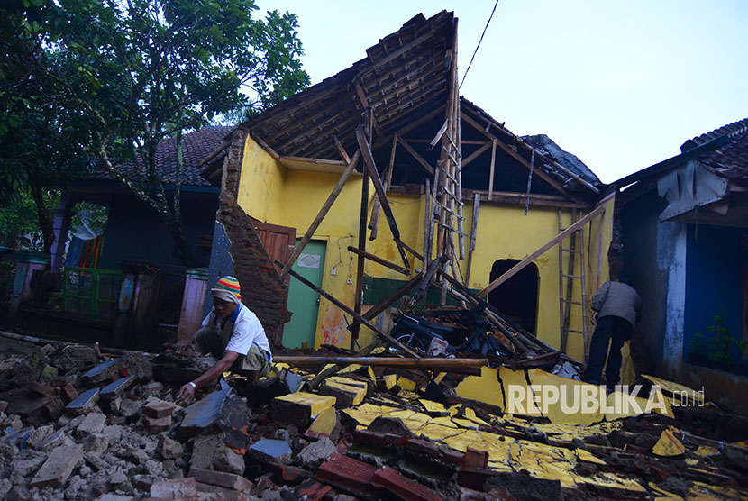 Warga membersihkan material reruntuhan bangunan rumah pasca gempa bumi di Desa Sumelap, Kota Tasikmalaya, Jawa Barat, Sabtu (16/12).