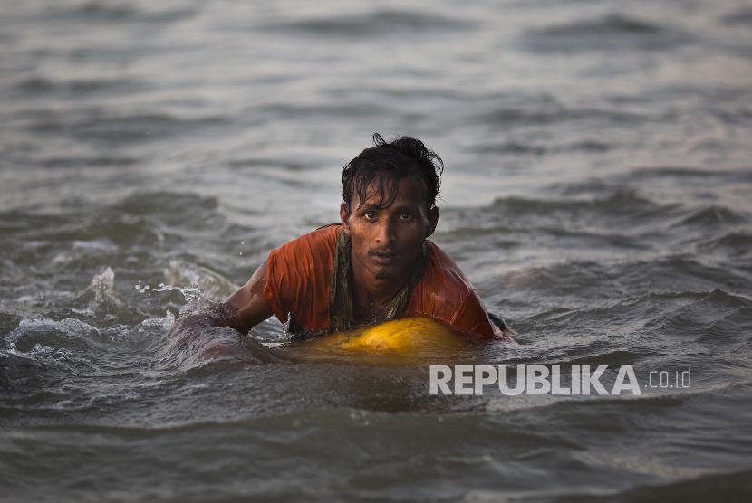 Seorang pria Rohingya berusaha melewati Sungai Naf di perbatasan Myanmar-Bangladesh, untuk melarikan diri dari genosida militer Myanmar terhadap muslim Rohingya. Pelapor Khusus PBB serukan militer Myanmar diselidiki atas kejahatan perang.