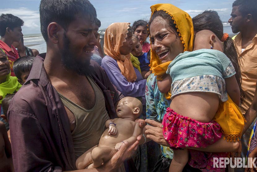Dalam foto file bulan September 2017, seorang pria Muslim Rohingya menggendong anak bayinya yang tewas akibat perahu yang mereka tumpangi tenggelam, ketika menyelematkan diri dari genosida militer Myanmar.