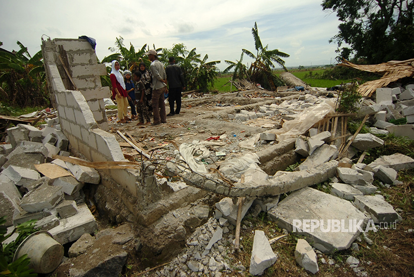 Sejumlah warga berada di dekat rumah yang hancur karena puting beliung di Desa Bojongnangka, Pemalang, Senin (1/1). 